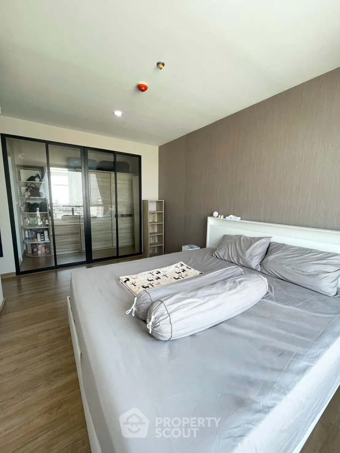 Modern bedroom with large bed and sliding glass wardrobe doors, featuring sleek design and ample natural light.