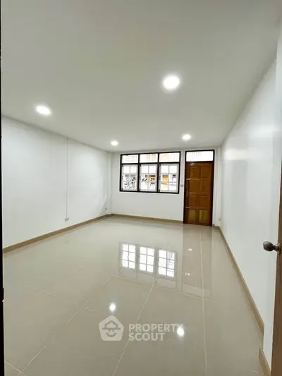 Spacious unfurnished room with large window and glossy tiled floor