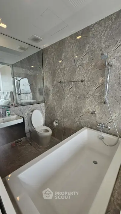 Luxurious modern bathroom with marble walls and sleek bathtub in high-end apartment.