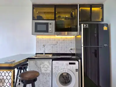 Modern kitchen with sleek appliances, washing machine, and stylish cabinetry in compact layout.