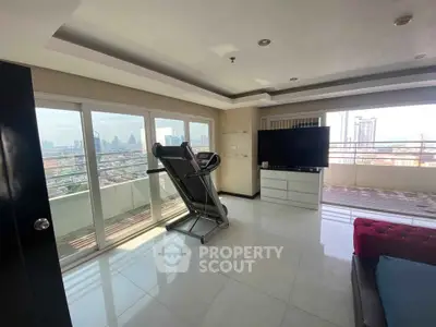 Spacious living room with treadmill and city view balcony in modern apartment