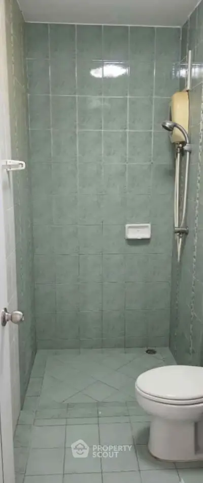 Compact bathroom with green tiles and shower in real estate property