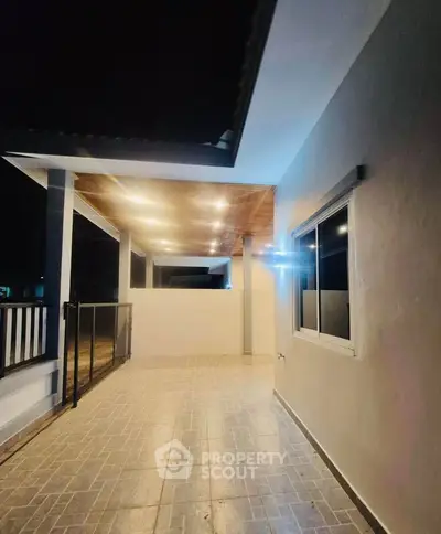 Spacious covered balcony with modern lighting and tiled flooring, perfect for evening relaxation.