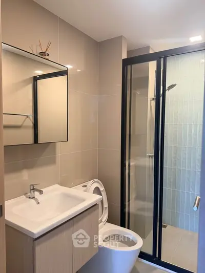 Modern bathroom with sleek fixtures and glass shower enclosure in contemporary apartment.