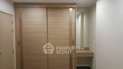 Modern minimalist bedroom with sliding wooden wardrobe and built-in vanity mirror.
