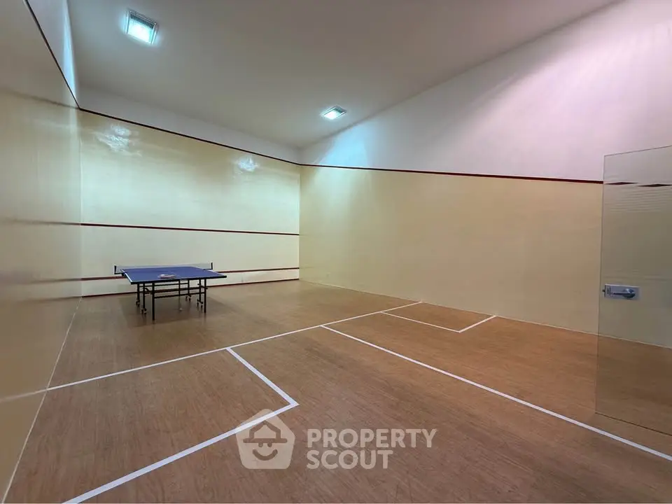 Spacious indoor squash court with wooden flooring and bright lighting