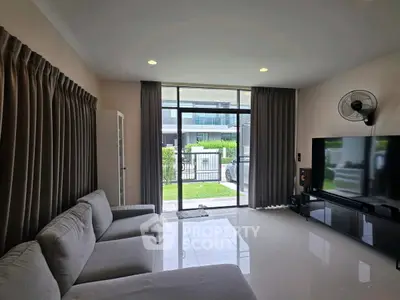 Modern living room with large windows and sleek furniture, offering a bright and inviting atmosphere.