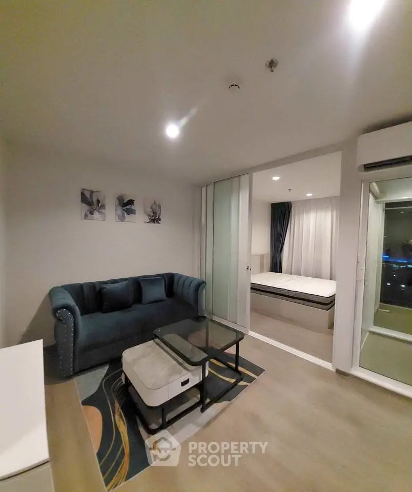 Modern living room with stylish sofa and glass coffee table, adjacent to a cozy bedroom with elegant decor.