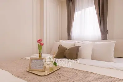 Elegant bedroom with cozy decor and soft lighting, featuring plush pillows and a stylish tray with flowers.