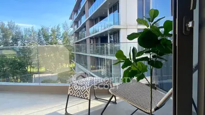 Modern balcony with stylish seating and lush green view in luxury apartment complex.
