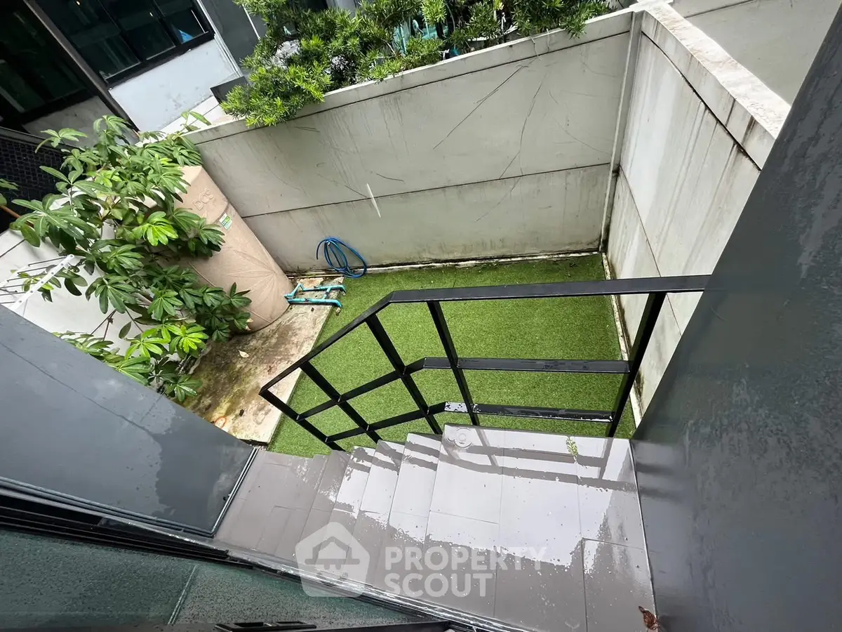 Modern urban garden with sleek metal staircase and lush greenery