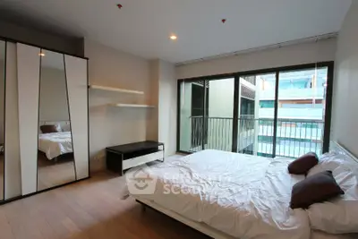 Spacious modern bedroom with large windows and balcony access in a stylish apartment.