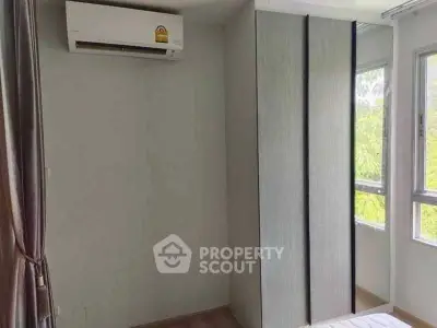 Bright bedroom with large window and built-in wardrobe, featuring air conditioning for comfort.
