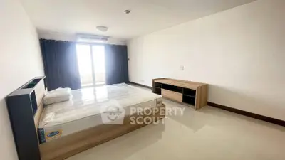 Spacious bedroom with modern furnishings and large window for natural light.
