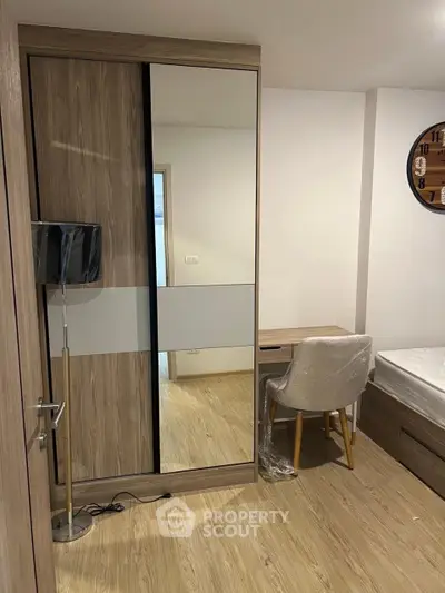 Modern bedroom with wooden flooring, stylish wardrobe, and cozy study area.