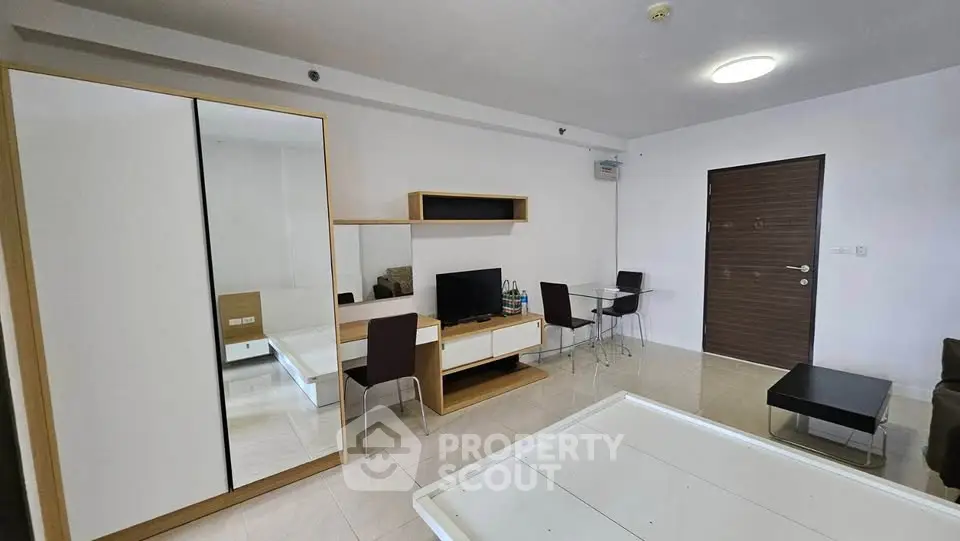 Modern living room with sleek furniture and minimalist design, featuring a TV and dining area.