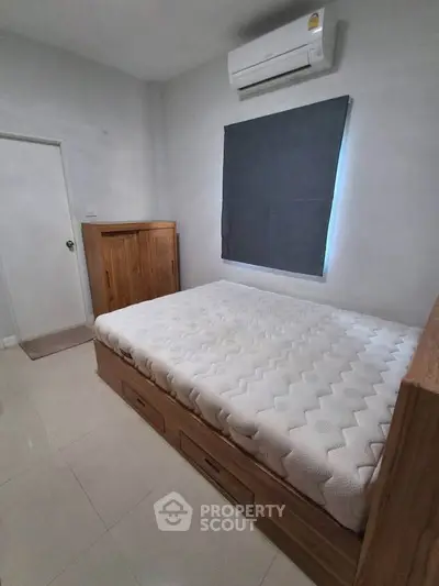 Cozy bedroom with modern air conditioning and stylish wooden furniture, perfect for a comfortable living experience.