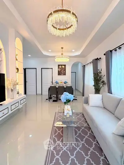 Elegant living room with modern chandelier and stylish decor, perfect for luxury living.