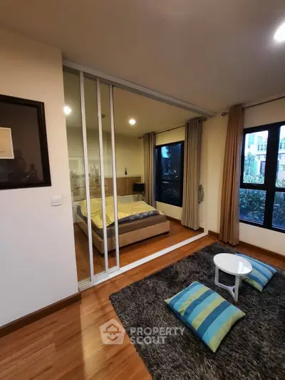Modern bedroom with sliding glass doors and cozy seating area, featuring stylish decor and natural light.