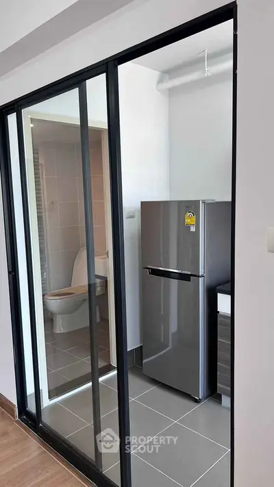 Modern apartment with sleek kitchen and bathroom design featuring sliding glass doors.