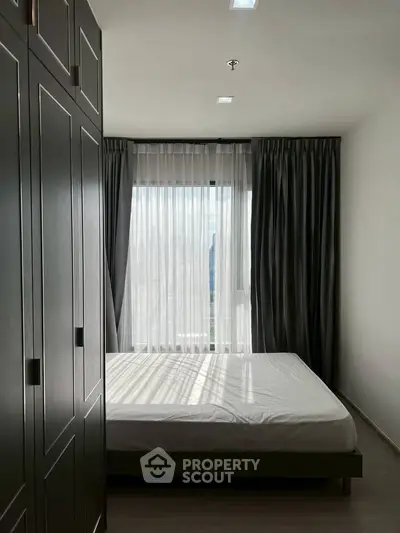 Modern bedroom with large window and stylish curtains in a contemporary apartment.