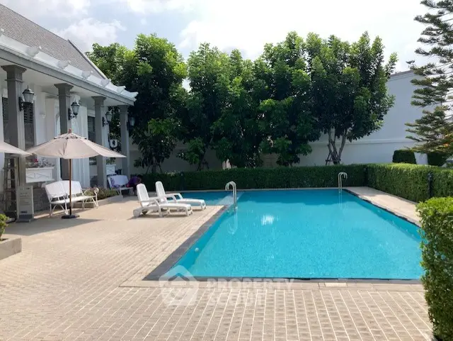 Luxurious outdoor pool area with elegant seating and lush greenery, perfect for relaxation and leisure.