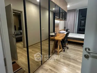 Modern bedroom with sleek mirrored wardrobe and cozy workspace