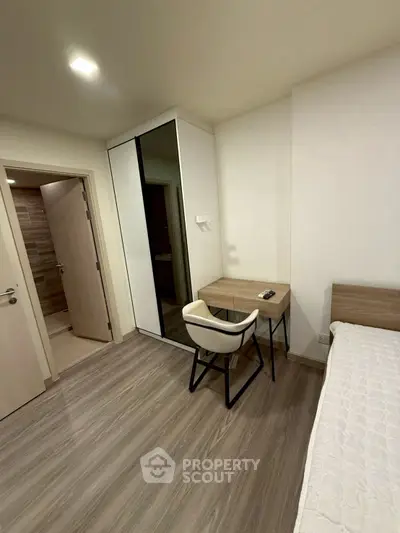 Modern bedroom with sleek design, featuring a minimalist desk and mirrored wardrobe.