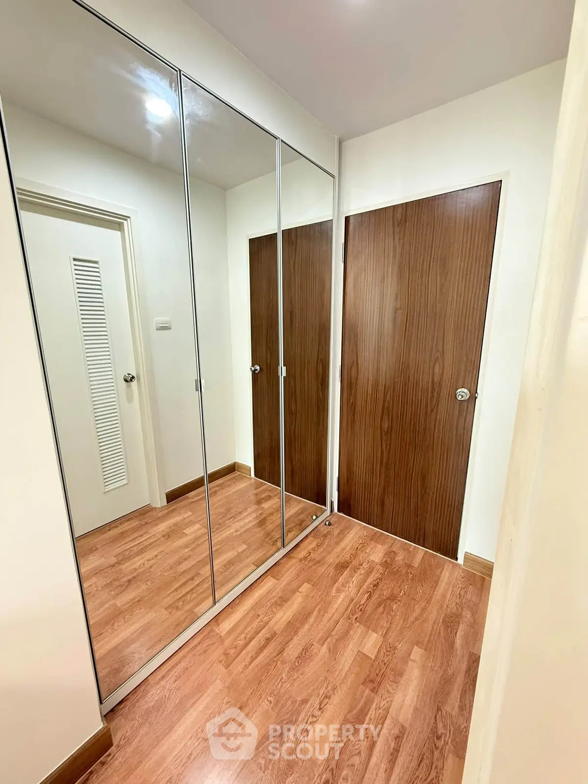 Modern hallway with mirrored closet doors and wooden flooring