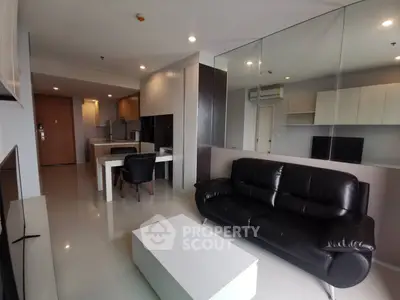 Modern living room with sleek black leather sofa and open kitchen layout