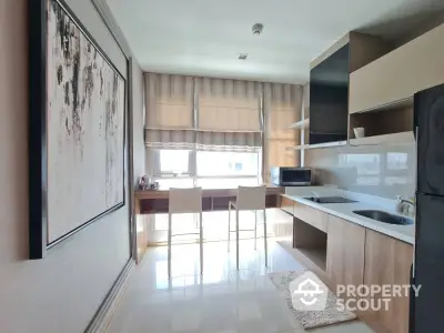 Modern kitchen with sleek design and natural light, featuring a breakfast bar and contemporary artwork.