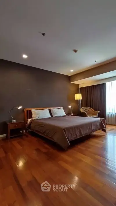 Spacious bedroom with wooden flooring and elegant decor