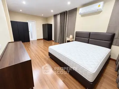 Spacious modern bedroom with wooden flooring and sleek furniture