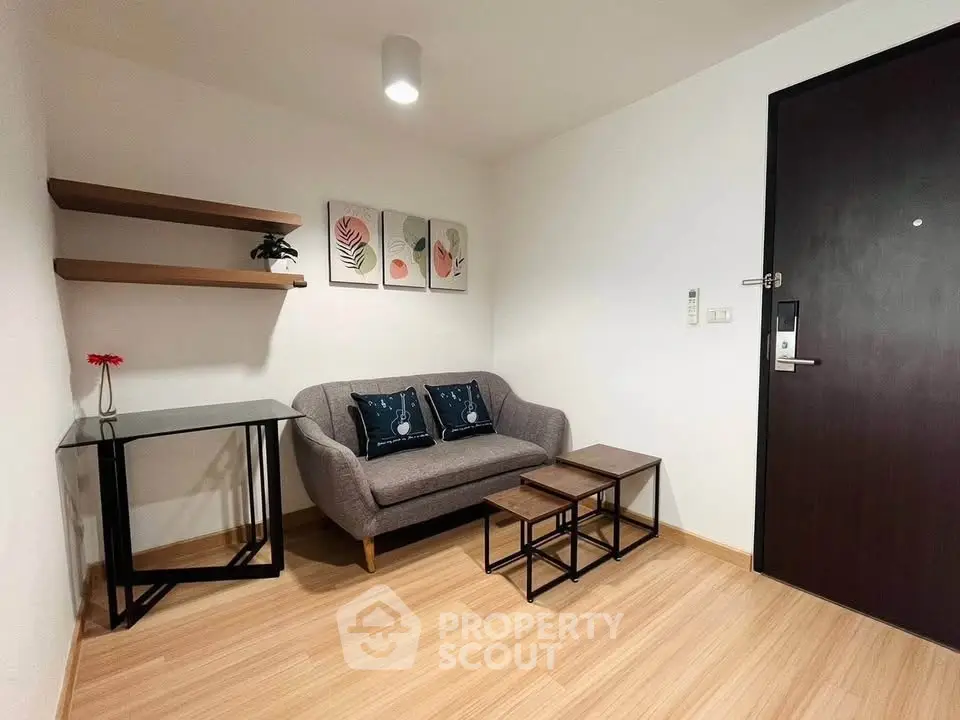 Modern living room with stylish sofa, nested tables, and wall art in a cozy apartment.