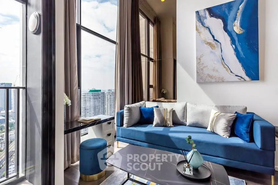 Luxurious living room with stunning city view, modern blue sofa, and elegant decor in high-rise apartment.