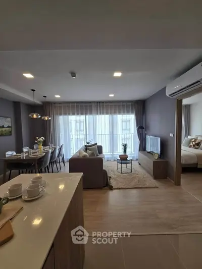 Modern open-plan living room with dining area and cozy bedroom in stylish apartment.
