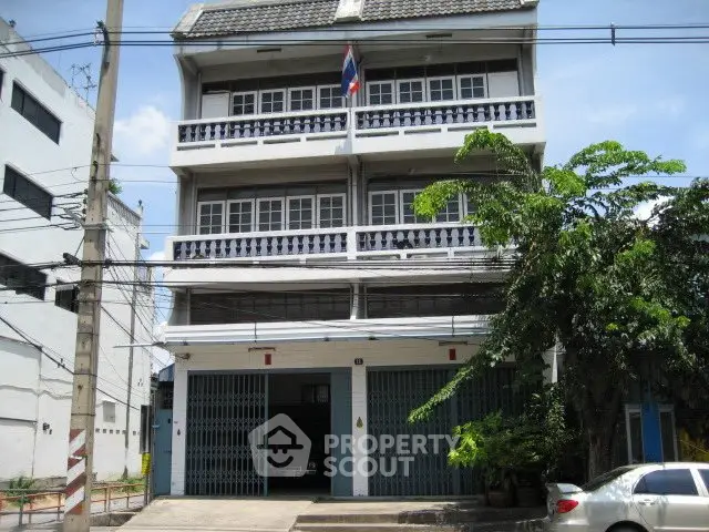 Charming three-story building with traditional balcony railings and lush greenery.