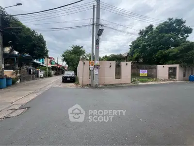 Street view of residential neighborhood with gated entrance and parked car.