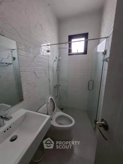 Modern bathroom with sleek white tiles and glass shower enclosure