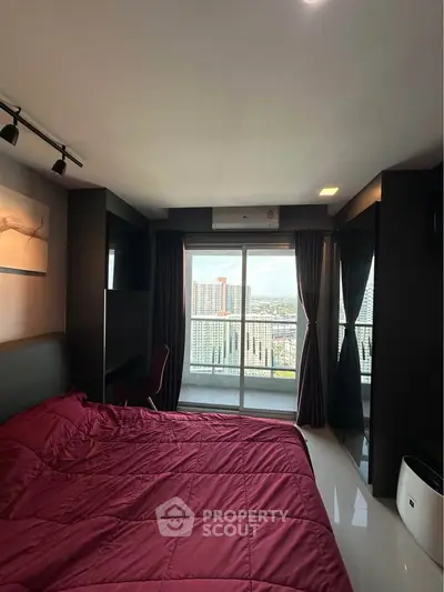 Modern bedroom with stunning city view and balcony access in high-rise apartment.