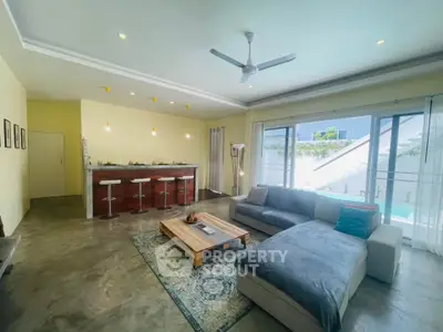 Spacious modern living room with open kitchen and pool view, perfect for entertaining.