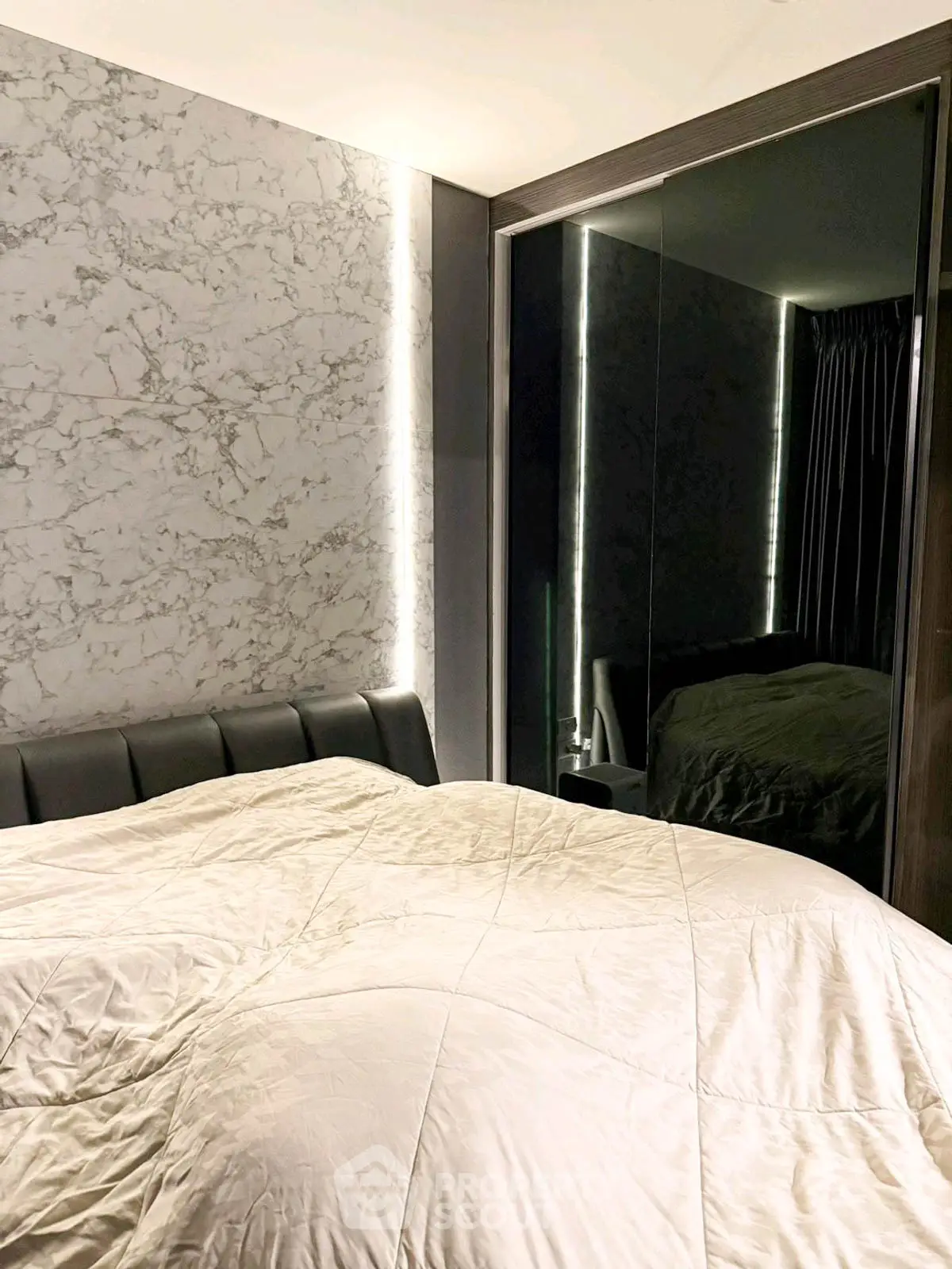 Luxurious bedroom with marble accent wall and mirrored wardrobe