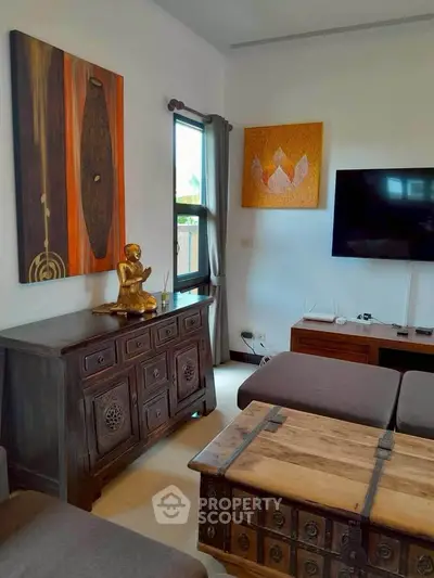 Charming living room with eclectic decor and wall art, featuring a flat-screen TV and wooden furniture.