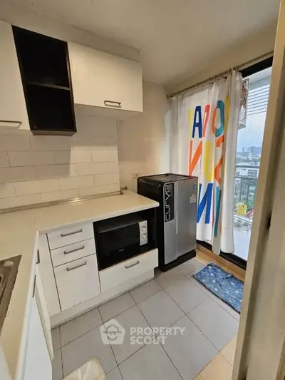 Modern kitchen with compact design, featuring built-in oven and balcony access with city view.