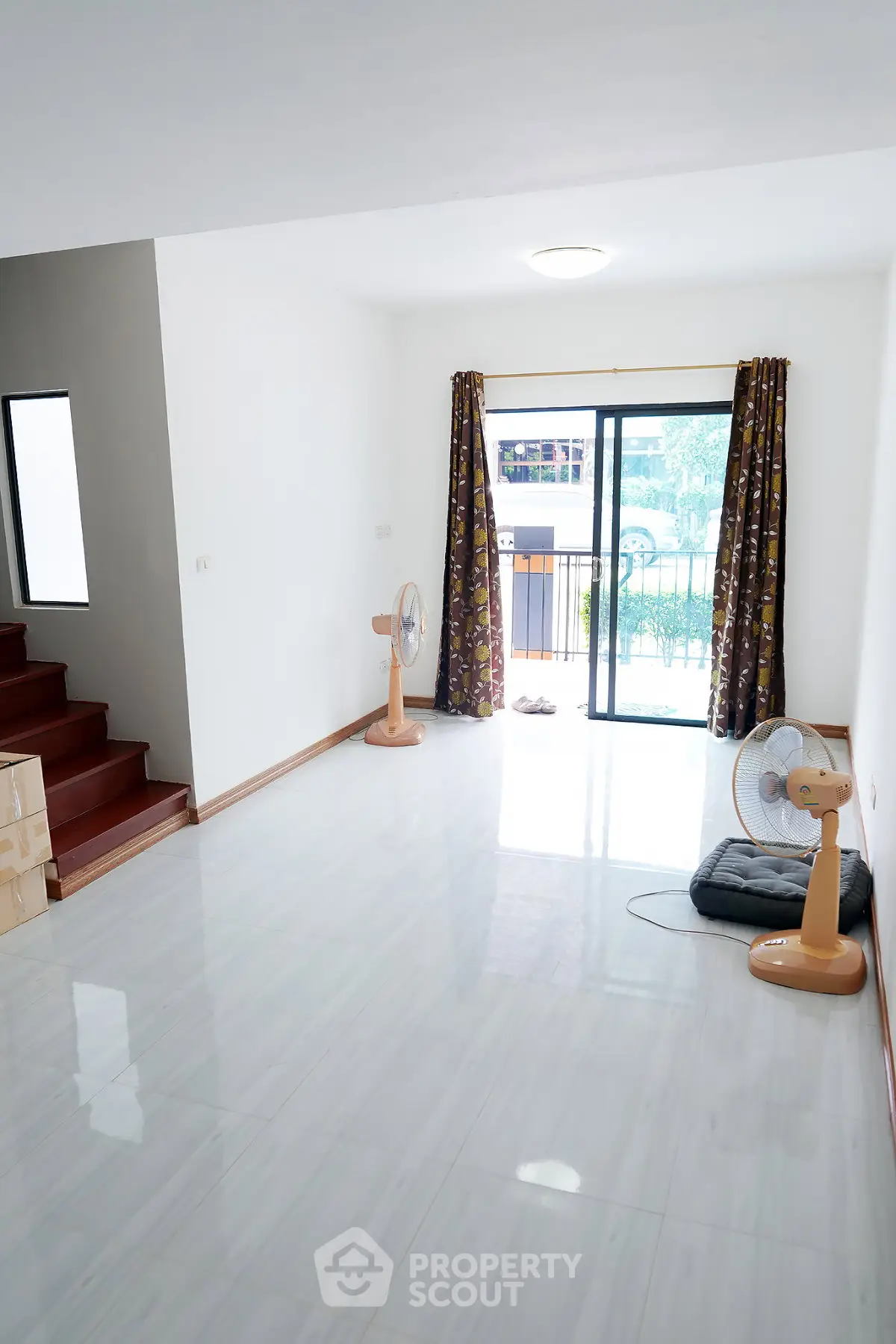 Spacious living room with large windows and modern flooring, perfect for natural light and comfort.