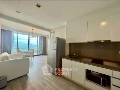Modern open-layout kitchen and living room with ocean view balcony in luxury apartment.