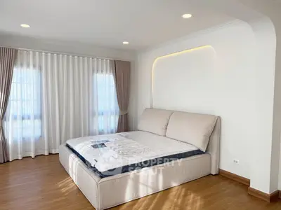 Spacious bedroom with elegant design and natural light, featuring a large bed and stylish curtains.