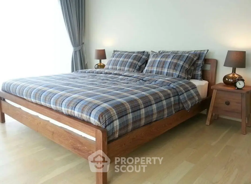 Cozy bedroom with wooden bed frame and plaid bedding, perfect for relaxation.