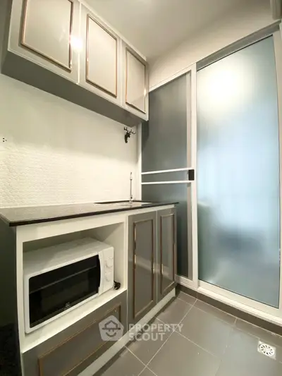 Modern compact kitchen with sleek cabinetry and built-in microwave