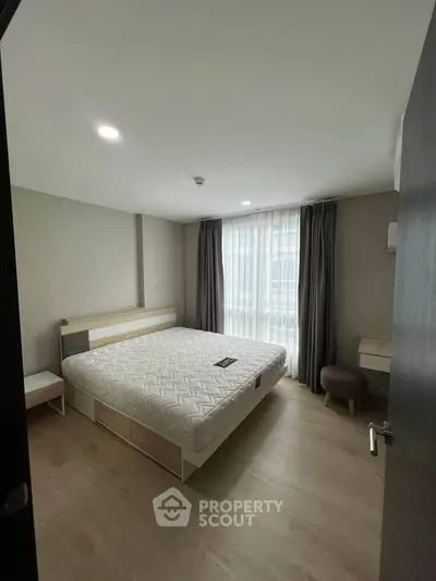 Modern bedroom with large window and stylish furnishings in a contemporary apartment.